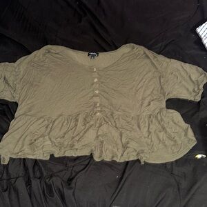 Navy green cropped top with ruffles at end of the shirt .